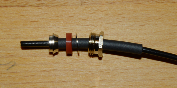 Abbildung 5: Vor dem Abisolieren des Geﬂechtes und des Innenleiters werden die vier ersten Teile auf das Kabel gesteckt. Das Befestigungsgewinde des rechten Teils weist in Richtung des Steckers. Dann kommt eine Art Beilagscheibe, die als Druckverteiler dient. Die Gummidichtung wird so montiert, dass der u-förmige Hohlraum genau auf die Schneide des Konus des nächsten Elementes passt. Das linke Element hat einen Anschlag und kann nicht weiter als gezeigt nach rechts geschoben werden.